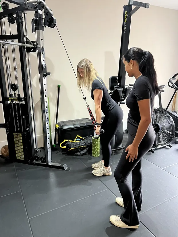 Ella demonstrating a cable exercise while a client watches