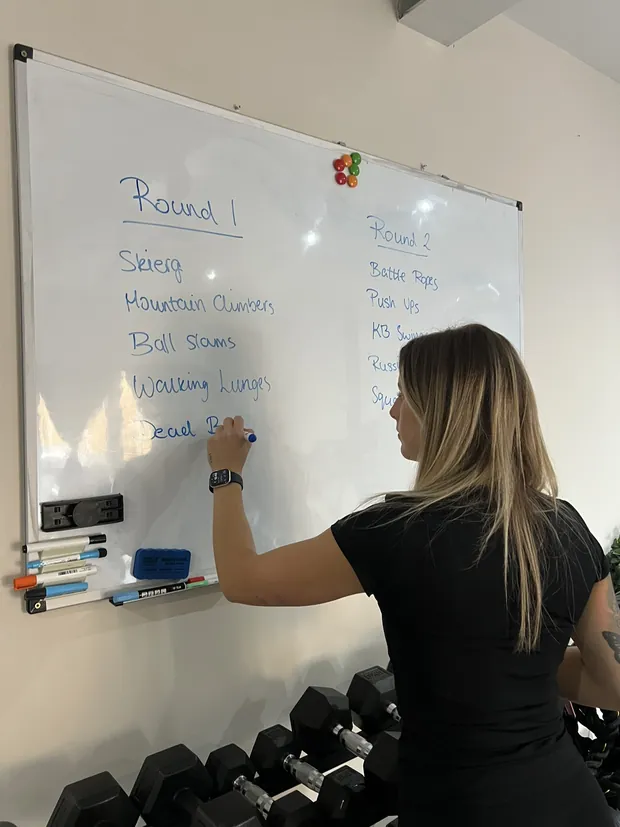 Ella writing the rounds for a class on the studio whiteboard