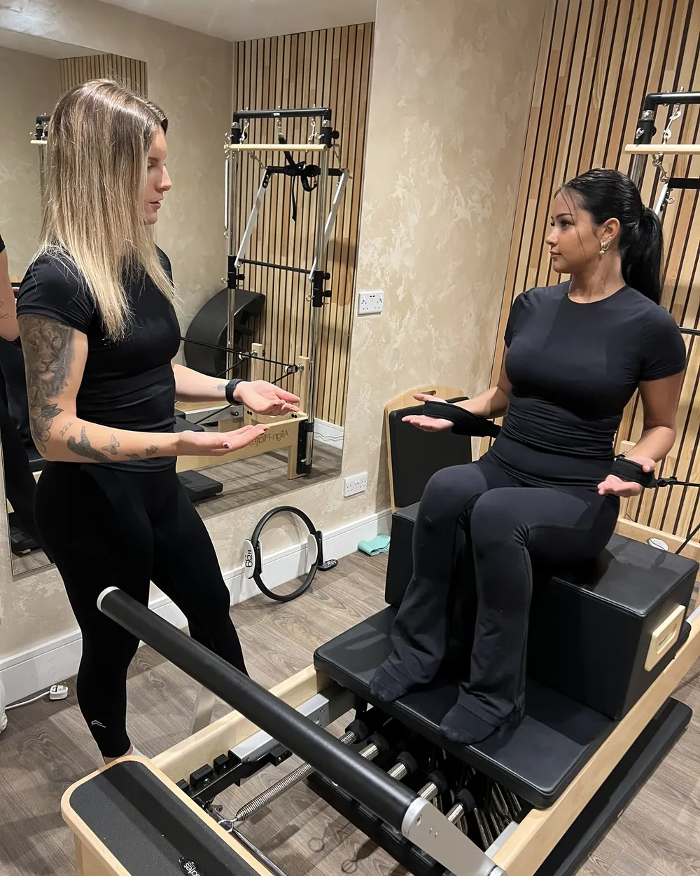 Ella guiding a client through a reformer Pilates exercise in the studio