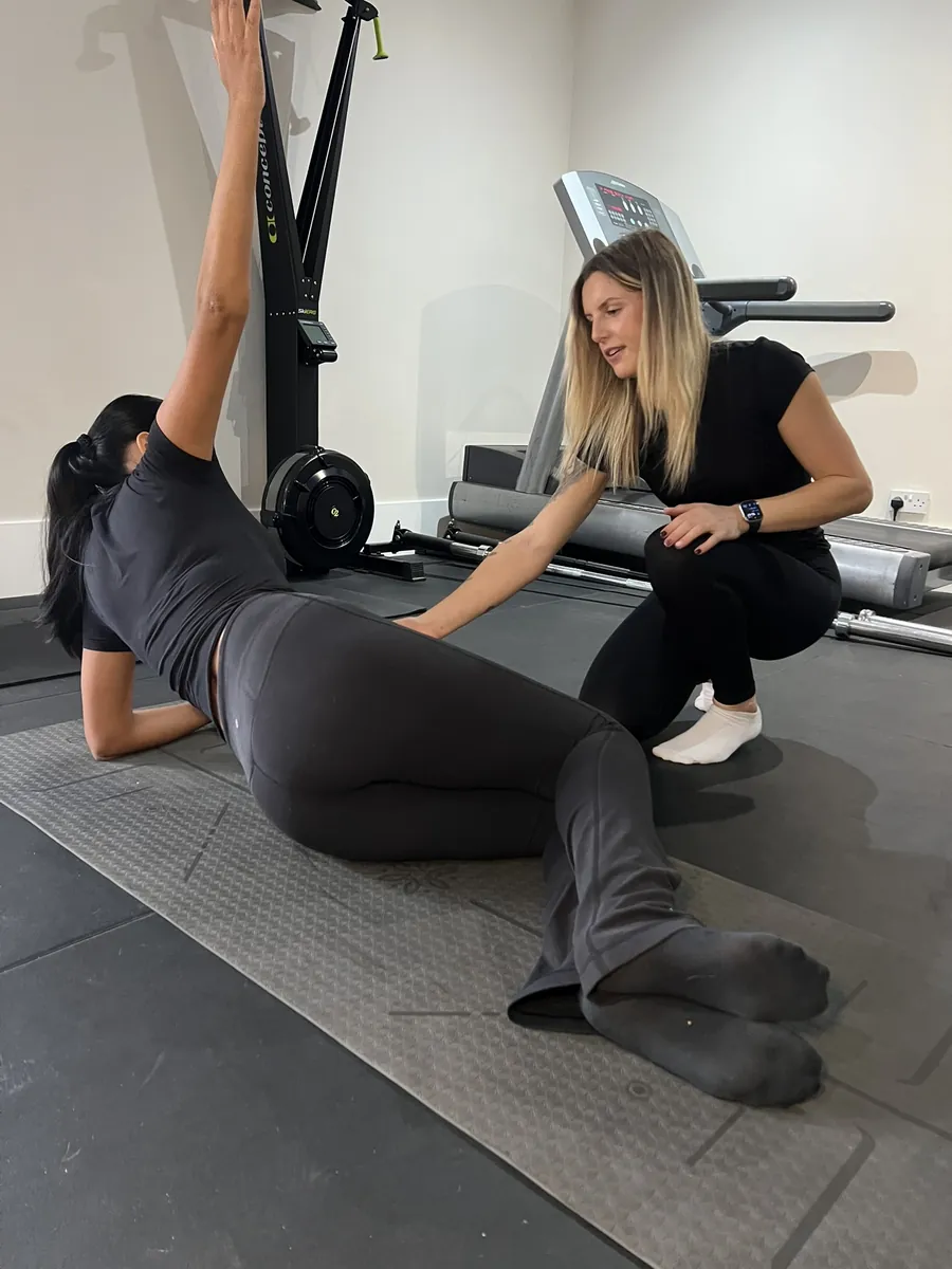 Ella correcting a client position during a mat Pilates exercise